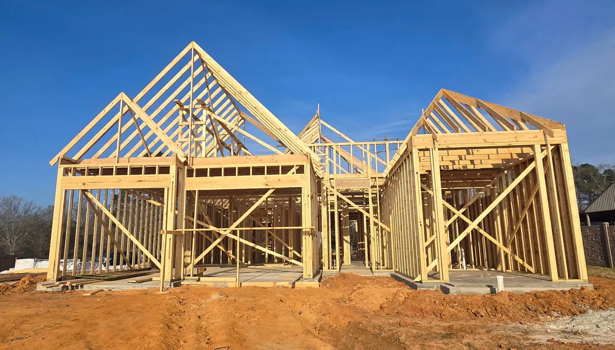 Framing of a Cutze custom home rising against a blue Louisiana sky