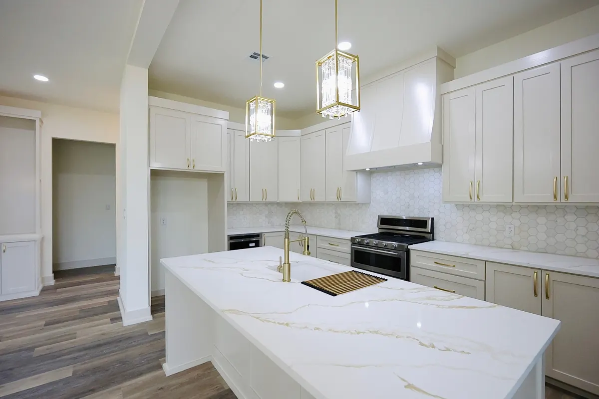 Custom kitchen in a Cutze-built home with quartz waterfall island and brass fixtures