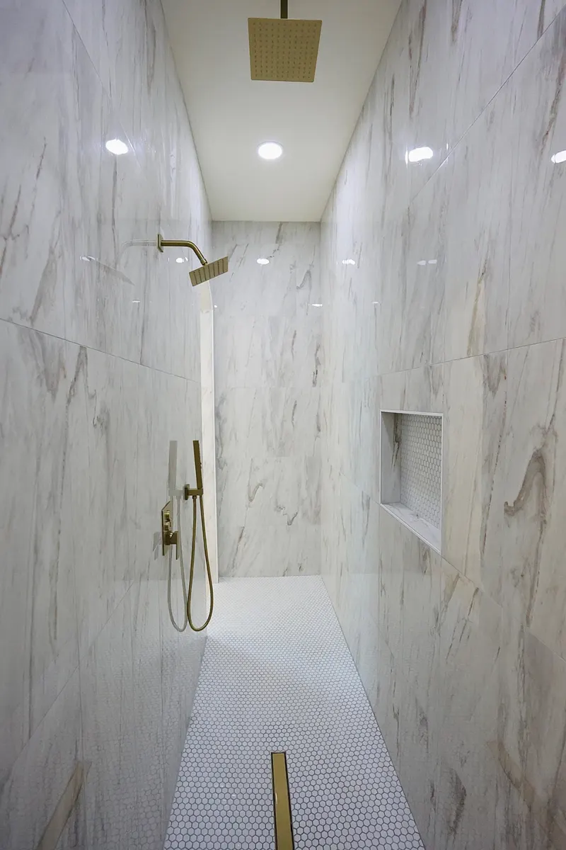 Walk-in marble shower with brass rain heads